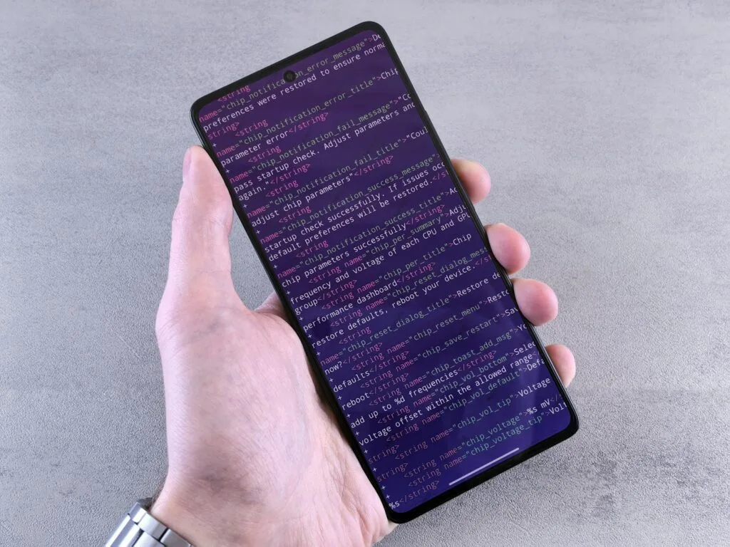 mobile app development in Egypt - hand holding smartphone displaying lines of code